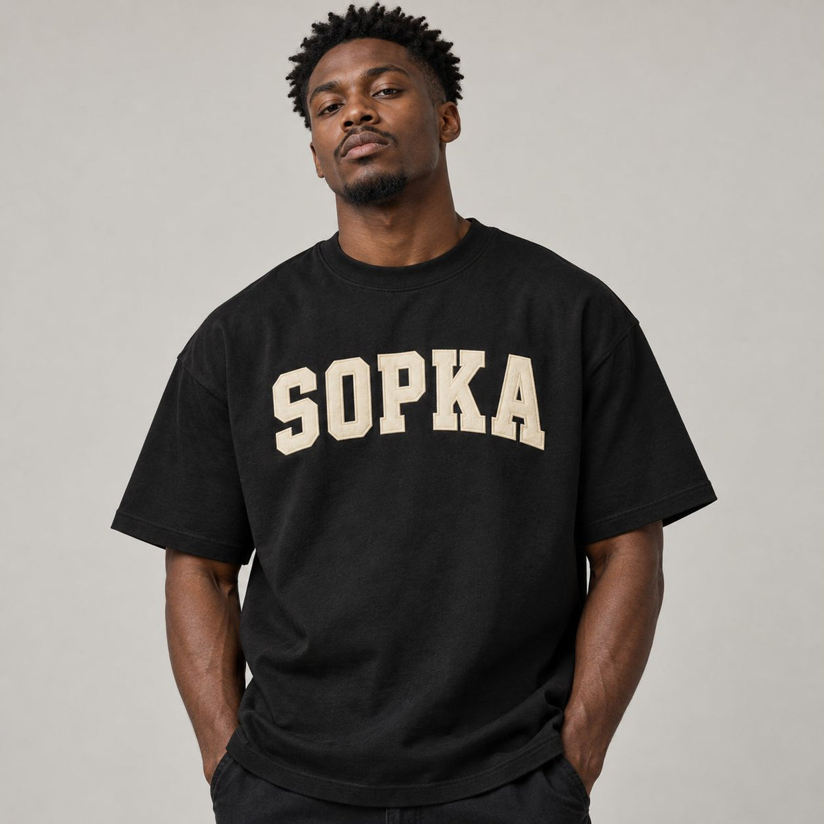 Black male model wearing black SOPKA varsity graphic T-shirt
